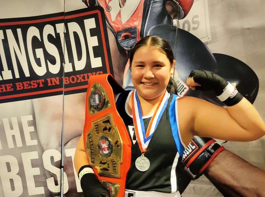 photo of young girl holding boxing belt flexing infront of promotional boxing poster